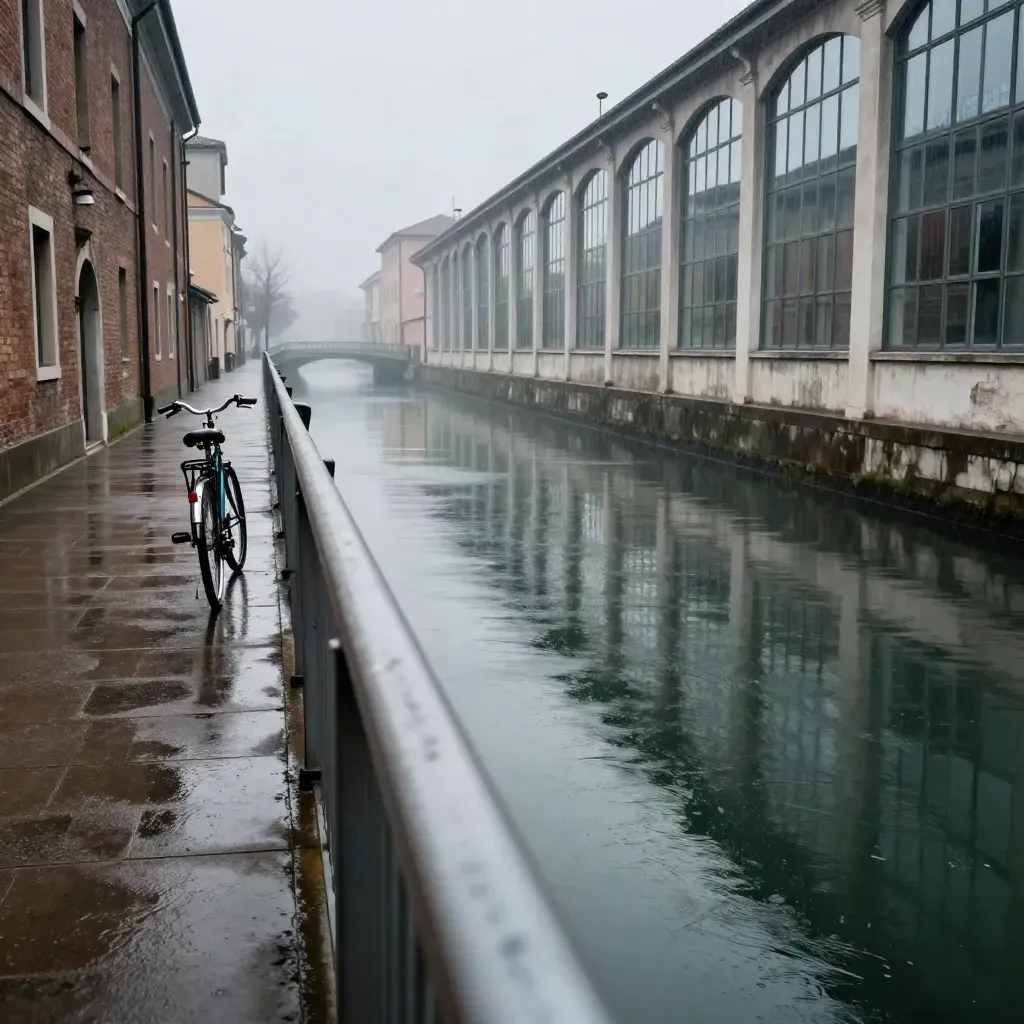 Canale industriale bagnato dalla pioggia con riflessi e una bicicletta legata alla ringhiera.